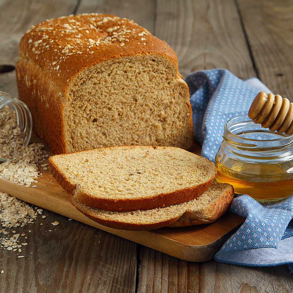 Sliced honey wheat bread loaf on a cutting board