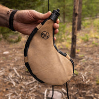 Thumbnail for Man holding tan leather bota bag in the outdoors.