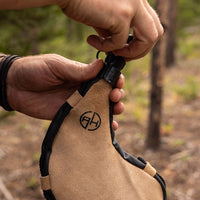 Thumbnail for Man unscrewing and removing drinking lid from tan leather bota bag outdoors.