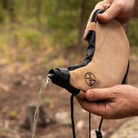 Thumbnail for Man tipping over and pouring the water out of a canteen pouch outdoors.