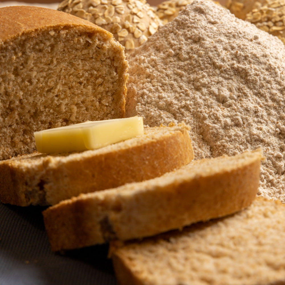 sliced bread from whole wheat flour next to a pile of raw whole wheat flour