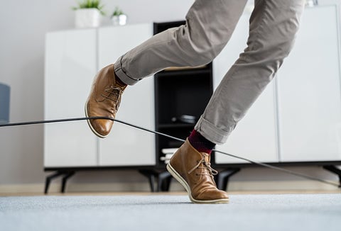 A man tripping over a wire set up to stop him.