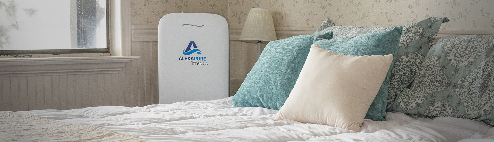 The Alexapure Breeze True Hepa Air Purifier sitting next to a bed
